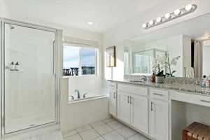 Primary Bathroom featuring separate shower and tub, tile patterned flooring, vanity, natural light, large window