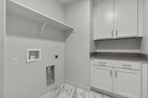 Washroom with electric dryer hookup, hookup for a washing machine, and cabinets