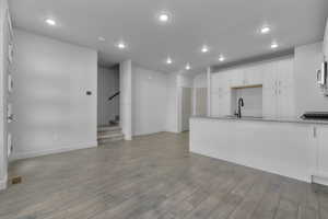 Kitchen with light hardwood / wood-style flooring, white cabinets, and sink