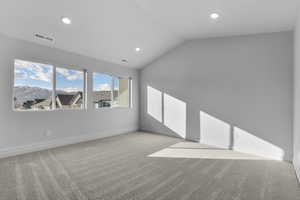 Carpeted empty room featuring a mountain view and lofted ceiling