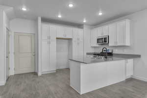 Kitchen featuring kitchen peninsula, light hardwood / wood-style floors, white cabinetry, and stainless steel appliances