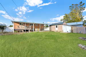 Back of house featuring a yard, an outbuilding, and a deck