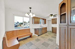 Kitchen with pendant lighting, ceiling fan with notable chandelier, stainless steel dishwasher, and sink