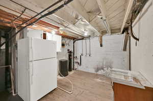 Basement with light hardwood / wood-style flooring and white fridge