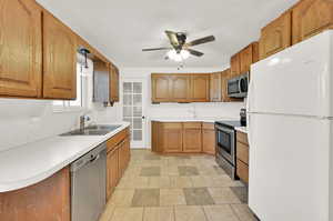 Kitchen featuring ceiling fan, sink, hanging light fixtures, and stainless steel appliances