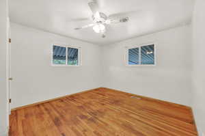 Unfurnished room with ceiling fan and hardwood / wood-style flooring