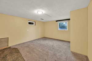 Carpeted spare room featuring a textured ceiling