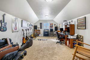 Carpeted office space with vaulted ceiling and a textured ceiling