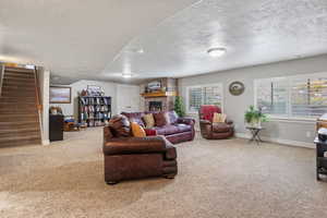 Carpeted living room with a fireplace, a healthy amount of sunlight, and a textured ceiling