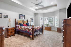 Bedroom featuring a raised ceiling, ceiling fan, and carpet floors