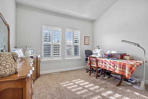 Carpeted home office featuring vaulted ceiling