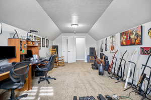 Office area with carpet, a textured ceiling, and lofted ceiling