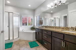 Bathroom featuring vanity, plus walk in shower, tile patterned flooring, and an inviting chandelier