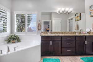 Bathroom with vanity, an inviting chandelier, and a bathing tub