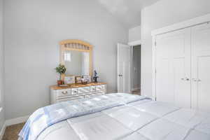 Carpeted bedroom featuring a closet and high vaulted ceiling