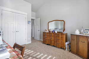 Bedroom featuring light carpet, a closet, and high vaulted ceiling