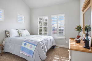 Bedroom with lofted ceiling and light colored carpet