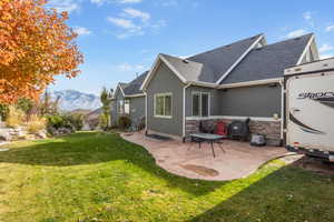 Rear view of property with a lawn, a patio area, and a mountain view