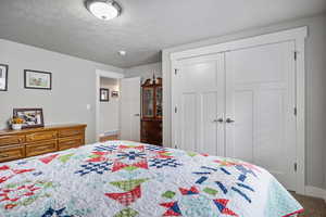 Bedroom with a closet, carpet floors, and a textured ceiling