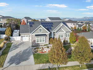 View of front of property with a front lawn, a mountain view, and solar panels