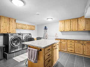 Washroom with washer and clothes dryer, cabinets, and a textured ceiling