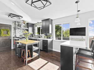 Kitchen featuring dark hardwood / wood-style floors, a kitchen breakfast bar, dishwasher, and tasteful backsplash