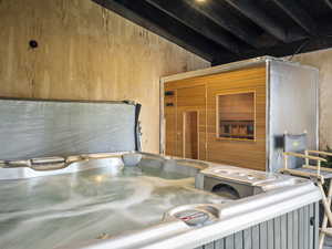 Interior space featuring a jacuzzi, vaulted ceiling with beams, and wooden walls