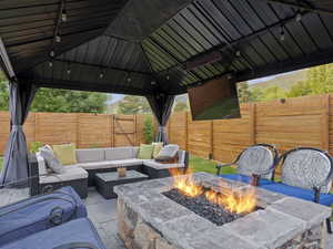 View of patio with a gazebo and an outdoor living space with a fire pit