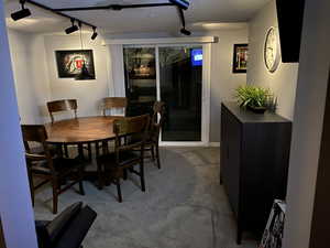 Dining space with carpet flooring, a textured ceiling, and rail lighting