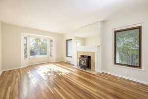 Living room featuring gas-burning stove, hardwood flooring, and sunny bay window