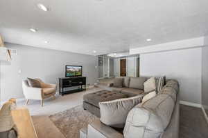 Carpeted living room featuring a textured ceiling