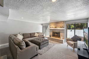 Carpeted living room featuring a large fireplace and a textured ceiling