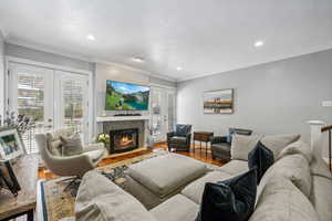 Living room featuring crown molding, wood-type flooring, and a tile fireplace