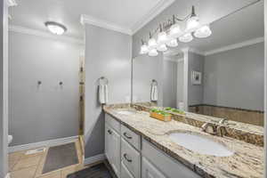 Bathroom with tile patterned floors, ornamental molding, and toilet