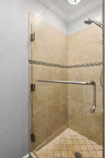 Bathroom featuring a shower with door and ornamental molding