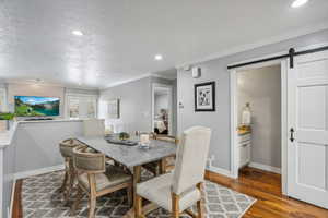 Dining room with hardwood / wood-style floors, ornamental molding, and a textured ceiling