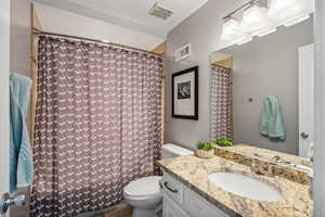 Bathroom featuring a textured ceiling, vanity, and toilet