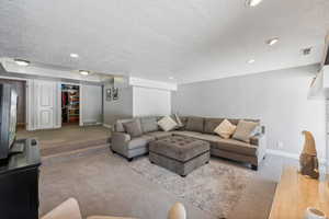 Carpeted living room featuring a textured ceiling