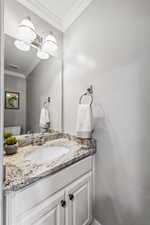 Bathroom with vanity, toilet, and crown molding