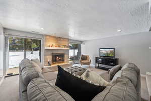 Carpeted living room with a fireplace, a wealth of natural light