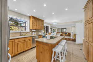 Kitchen featuring a breakfast bar, stainless steel appliances, sink, light tile patterned floors, and a kitchen island