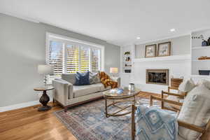 Living room with hardwood / wood-style floors and ornamental molding