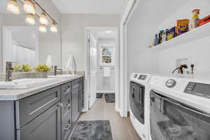 Washroom featuring washer and clothes dryer, sink, and light tile patterned floors