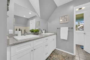 Bathroom with tile patterned flooring, vanity, and vaulted ceiling