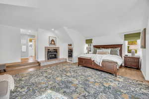 Bedroom featuring lofted ceiling, a tile fireplace, and light wood-type flooring