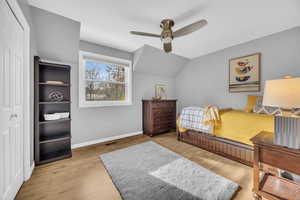 Bedroom featuring light wood-type flooring, a closet, lofted ceiling, and ceiling fan