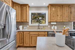 Kitchen with decorative backsplash, sink, light tile patterned flooring, and stainless steel appliances