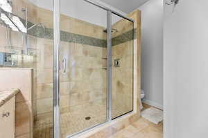 Bathroom with tile patterned flooring, vanity, toilet, and walk in shower