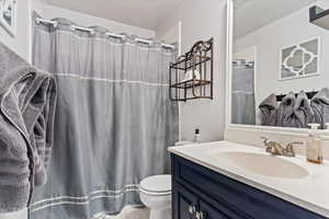 Bathroom featuring vanity, tile patterned flooring, a textured ceiling, and toilet