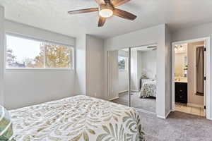 Bedroom with a closet, ensuite bath, carpet floors, a textured ceiling, and ceiling fan